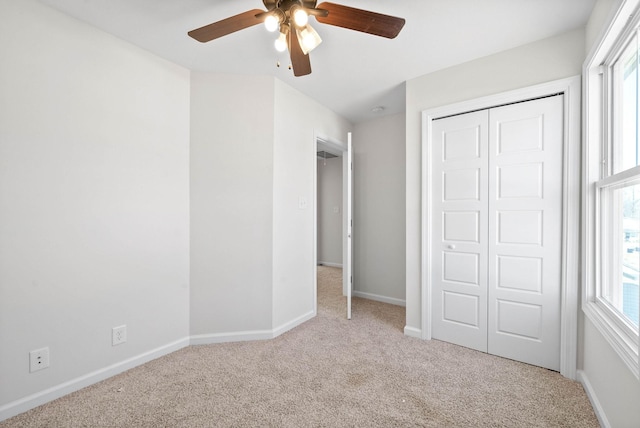 unfurnished bedroom featuring light colored carpet, ceiling fan, and a closet