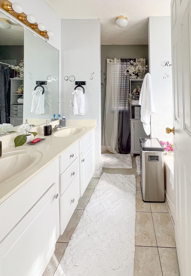 bathroom with tile patterned flooring, vanity, and a textured ceiling