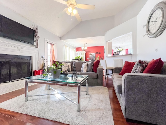 living room with lofted ceiling, ceiling fan with notable chandelier, and dark hardwood / wood-style flooring