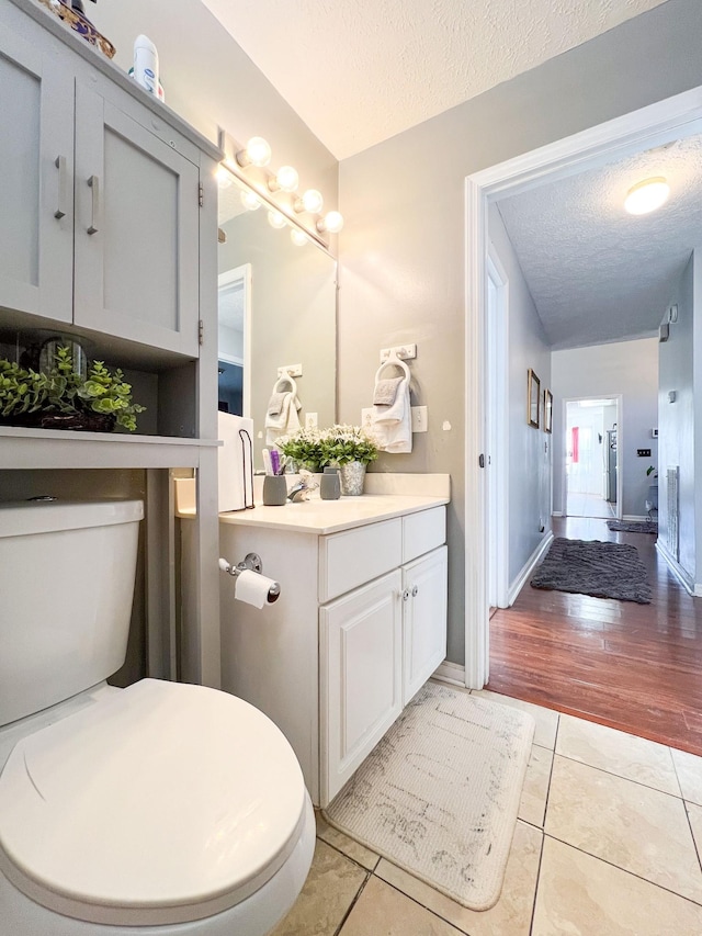 bathroom with vanity, tile patterned flooring, toilet, and a textured ceiling