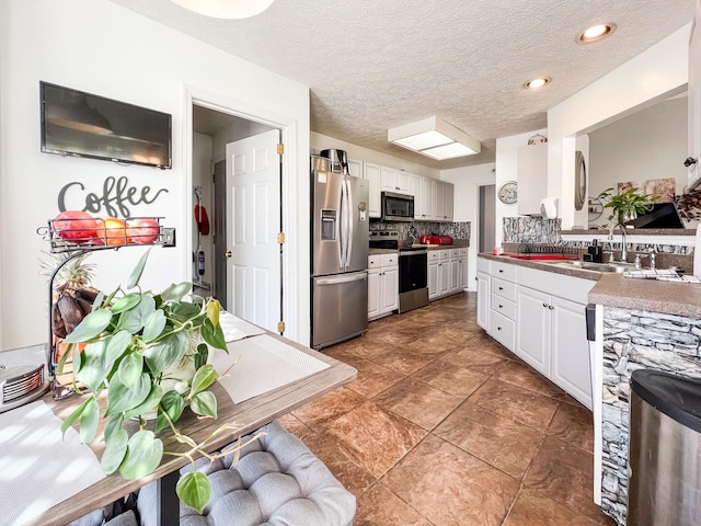 kitchen featuring sink, stainless steel appliances, tasteful backsplash, a textured ceiling, and white cabinets