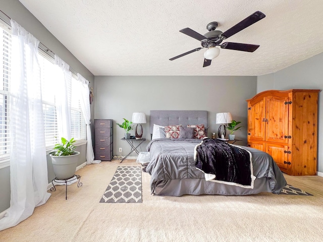 carpeted bedroom with ceiling fan and a textured ceiling