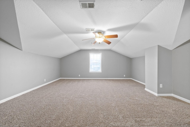 additional living space featuring ceiling fan, lofted ceiling, carpet, and a textured ceiling