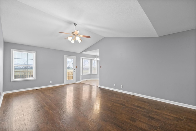 unfurnished living room featuring dark hardwood / wood-style flooring, ceiling fan with notable chandelier, and lofted ceiling