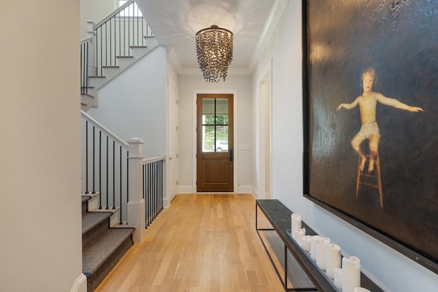 foyer featuring ornamental molding, a chandelier, and light hardwood / wood-style flooring