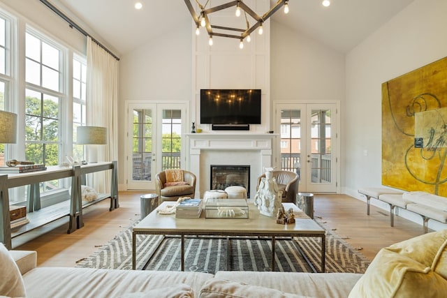 living room with light hardwood / wood-style flooring, high vaulted ceiling, a large fireplace, and french doors