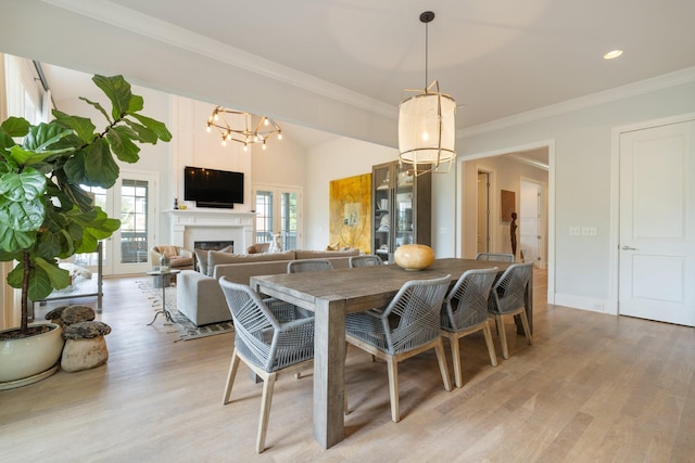 dining space with an inviting chandelier, ornamental molding, and light hardwood / wood-style flooring