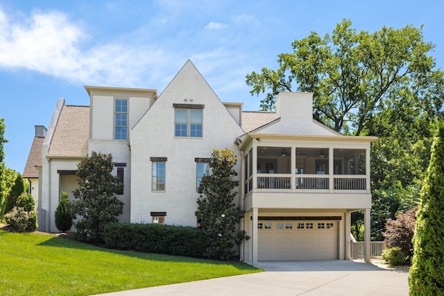 view of front of property featuring a garage, a sunroom, a front yard, and ceiling fan