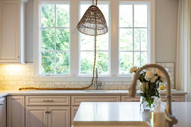 kitchen with pendant lighting, decorative backsplash, plenty of natural light, and white cabinets