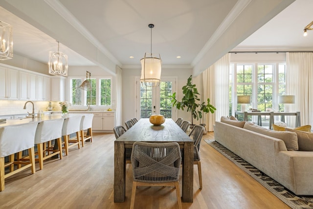 dining area featuring an inviting chandelier, ornamental molding, light hardwood / wood-style floors, and french doors