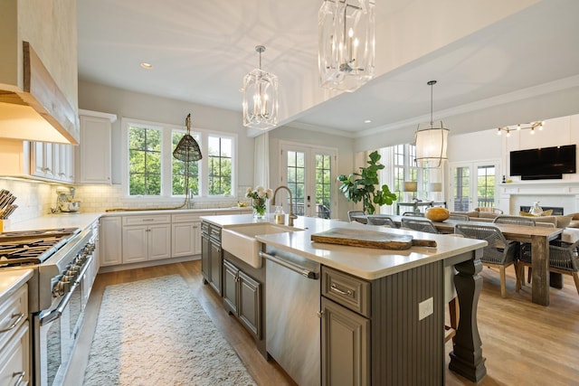 kitchen with french doors, a kitchen bar, white cabinetry, a center island with sink, and appliances with stainless steel finishes