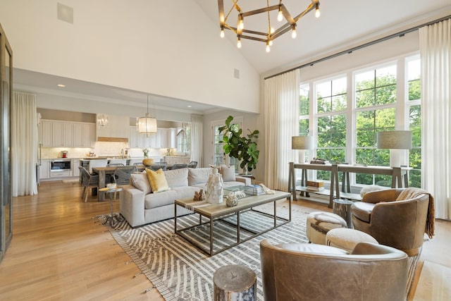 living room with a notable chandelier, high vaulted ceiling, and light wood-type flooring