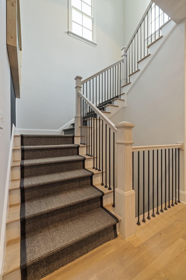 stairway with hardwood / wood-style flooring and a towering ceiling