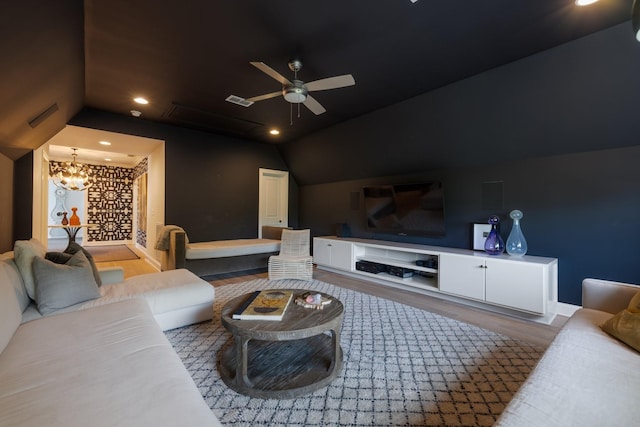 cinema room with ceiling fan with notable chandelier, lofted ceiling, and hardwood / wood-style floors