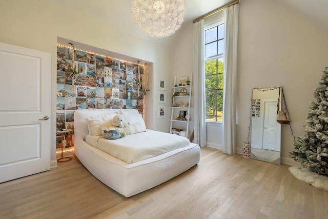 bedroom featuring hardwood / wood-style floors, a towering ceiling, and a notable chandelier