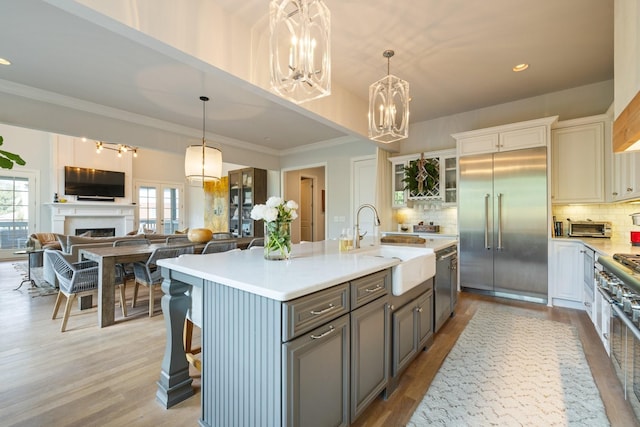 kitchen featuring white cabinetry, sink, a breakfast bar area, premium appliances, and a center island with sink