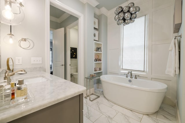 bathroom with vanity, crown molding, a tub, and toilet