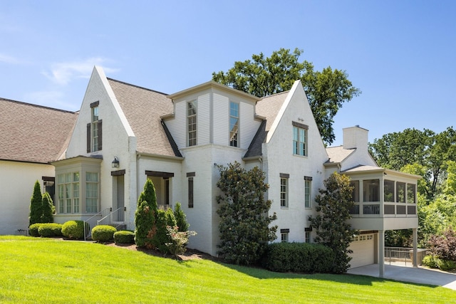 view of front of house featuring a garage, a sunroom, and a front yard