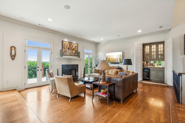 living room with wood-type flooring, beverage cooler, crown molding, and french doors