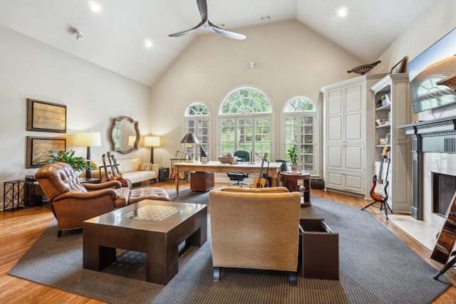 living room featuring hardwood / wood-style flooring, a fireplace, high vaulted ceiling, and ceiling fan