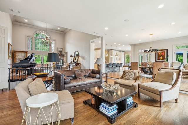 living room featuring ornamental molding, a chandelier, and light hardwood / wood-style floors