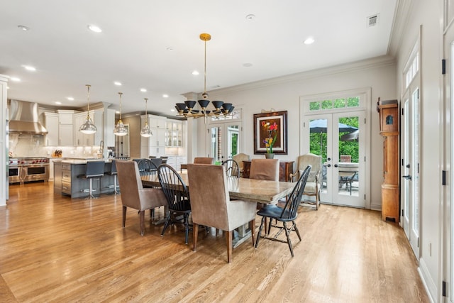 dining area with crown molding, light hardwood / wood-style floors, and french doors