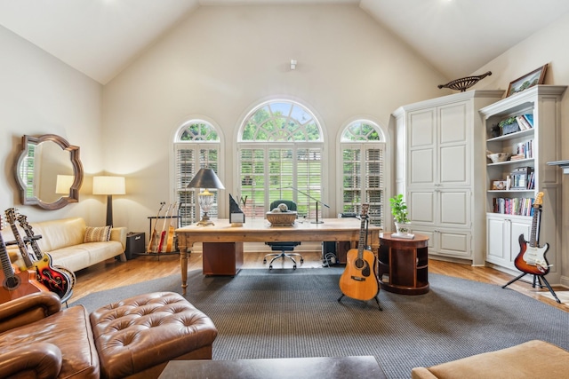 office space with a healthy amount of sunlight, high vaulted ceiling, and light wood-type flooring