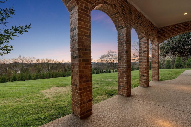 patio terrace at dusk featuring a lawn