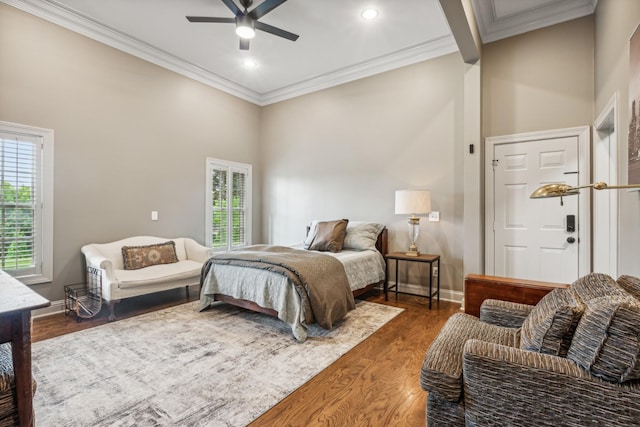 bedroom featuring dark wood-type flooring, a towering ceiling, ornamental molding, and ceiling fan