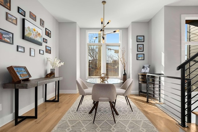 dining room with a chandelier, light wood-style flooring, and baseboards