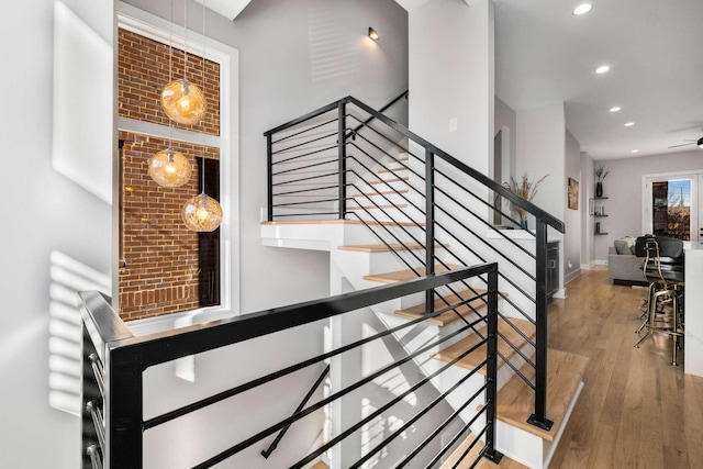 stairway featuring baseboards, wood finished floors, and recessed lighting