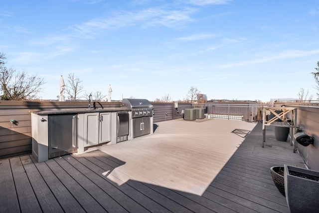 wooden deck featuring central AC unit, an outdoor kitchen, and a grill