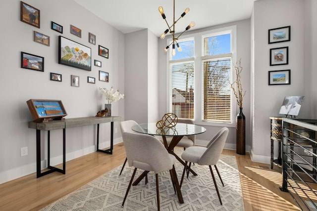 dining room with light wood finished floors, baseboards, and an inviting chandelier