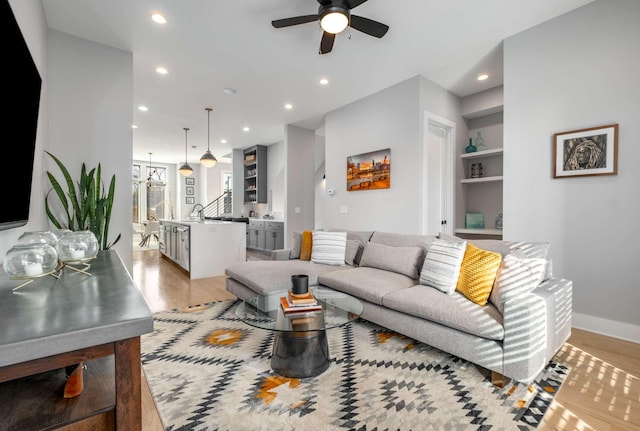 living area featuring built in shelves, light wood-type flooring, and recessed lighting