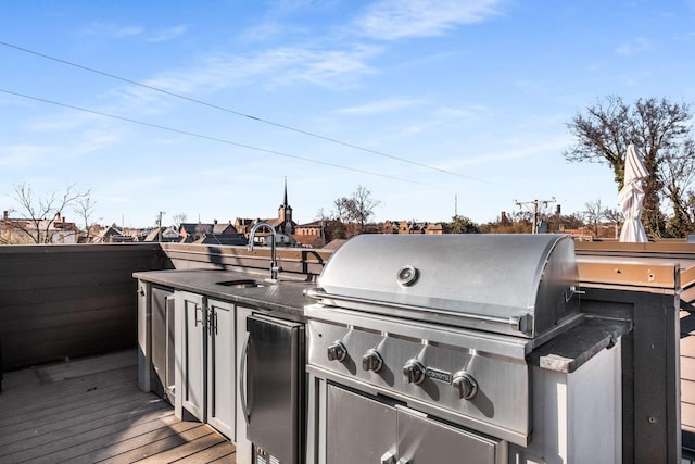 view of patio with exterior kitchen, a sink, a wooden deck, and area for grilling