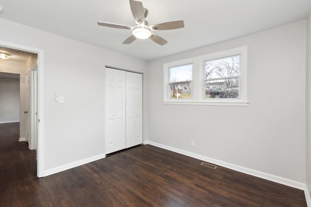 unfurnished bedroom featuring ceiling fan, dark hardwood / wood-style flooring, and a closet