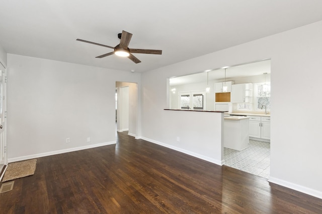 unfurnished living room featuring hardwood / wood-style floors, sink, and ceiling fan