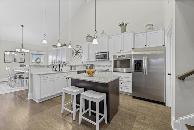 kitchen with sink, appliances with stainless steel finishes, a kitchen island, pendant lighting, and white cabinets