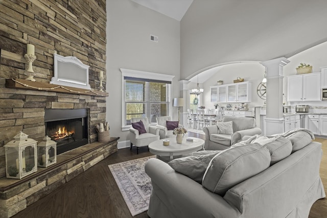 living room featuring ornate columns, dark hardwood / wood-style flooring, high vaulted ceiling, and a fireplace