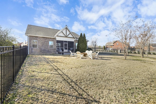 back of house featuring a sunroom, a lawn, and a fire pit