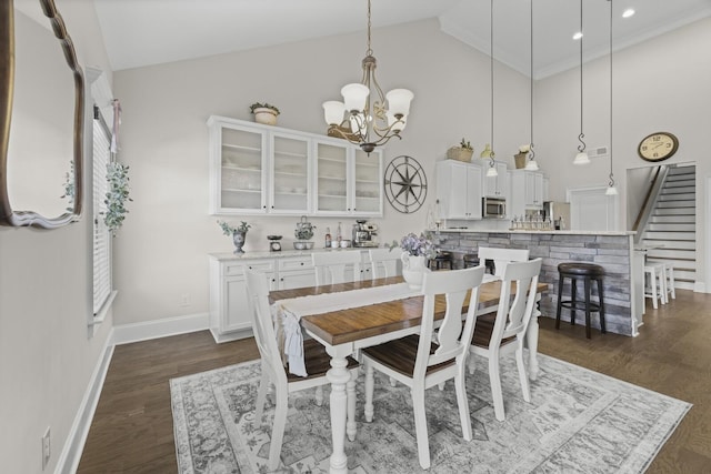 dining room with dark hardwood / wood-style flooring, high vaulted ceiling, and a chandelier