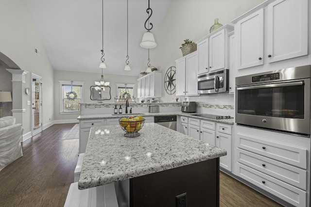 kitchen featuring pendant lighting, sink, appliances with stainless steel finishes, white cabinetry, and a kitchen island