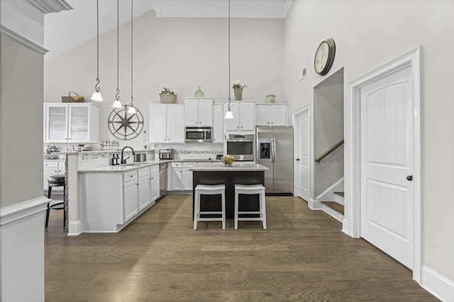 kitchen featuring a kitchen breakfast bar, stainless steel appliances, white cabinets, a kitchen island, and decorative light fixtures