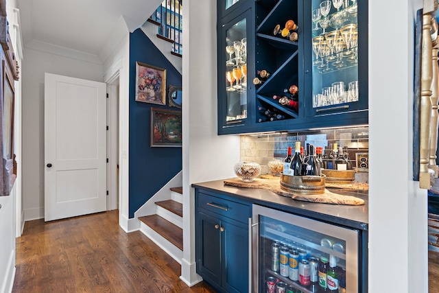 bar with tasteful backsplash, wine cooler, dark wood-type flooring, crown molding, and blue cabinetry