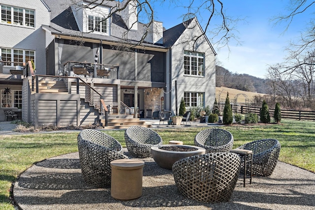 rear view of house with a yard, a sunroom, a patio area, and a fire pit