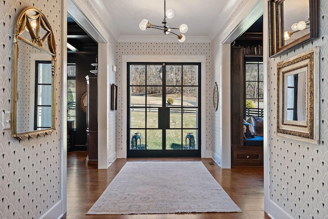 foyer featuring an inviting chandelier, crown molding, dark hardwood / wood-style floors, and a healthy amount of sunlight