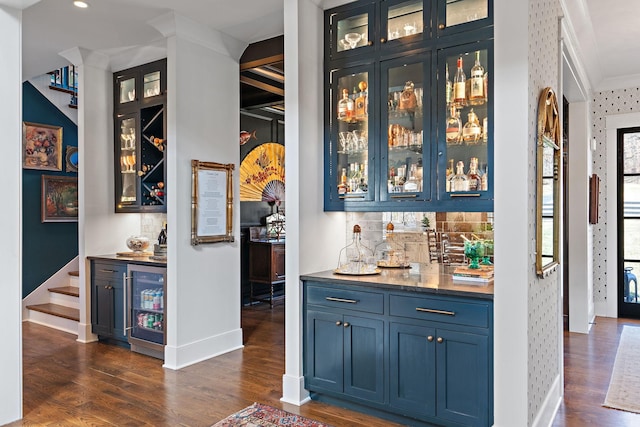 bar with crown molding, dark wood-type flooring, blue cabinetry, backsplash, and beverage cooler