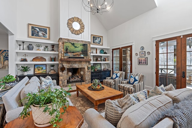 living room with built in features, high vaulted ceiling, a stone fireplace, french doors, and a chandelier