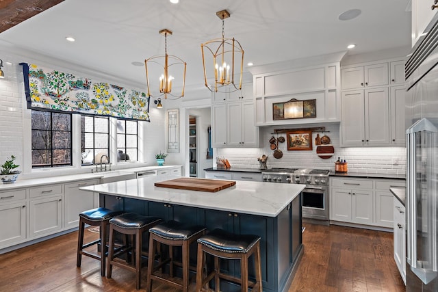 kitchen featuring a kitchen island, decorative light fixtures, white cabinetry, sink, and high end appliances