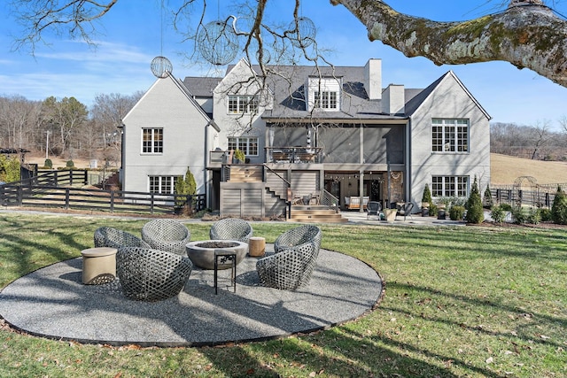 rear view of property featuring a yard, a sunroom, a patio, and an outdoor fire pit